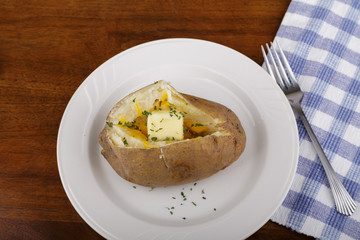 Baked Potato on Plate with Cheese Butter and Parsley