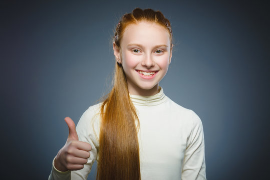 Happy girl showing thub up. Closeup Portrait child smiling isolated on grey