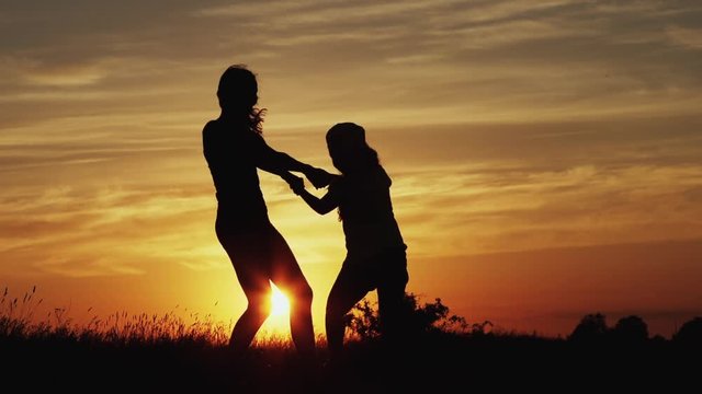 Two Friends Hold Hands And Spin In Circles In A Beautiful Day At Sunset