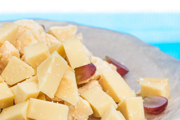 Detailed close-up on parmigiano pieces with grape ona wooden plate.