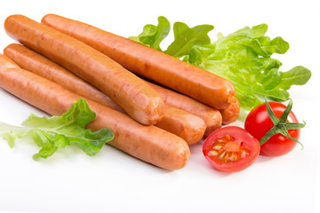 Long sausages, green salad, tomatoes on white.