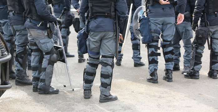 group of police officers in riot control with batons during secu
