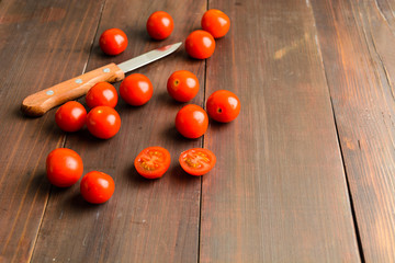 Fototapeta na wymiar Many cherry tomatoes and knife on brown wooden background