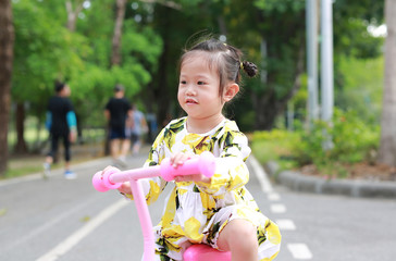 Cute little child girl riding bike in park.