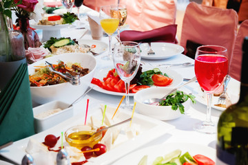 Table set for banquet with cutlery. Salads, appetizers and glasses with wine.