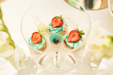 Delicious and tasty dessert table with cupcakes shots at reception closeup