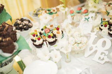 Delicious and tasty dessert table with cupcakes shots at reception closeup