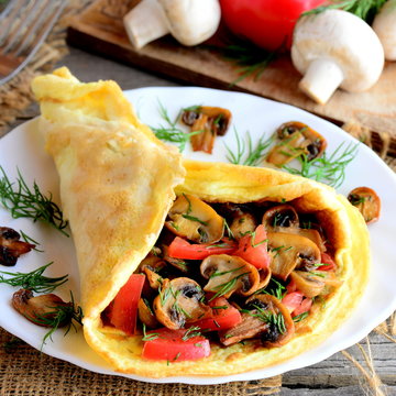 Mushrooms omelette with fresh tomatoes and dill on a white plate and on a wooden table. Rustic style. Closeup