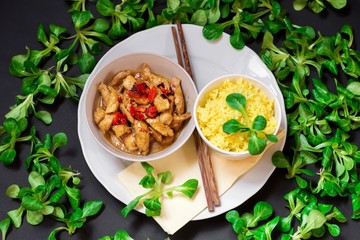 Turkey meat strips, curry rice on white, chopstick, many lam ´s lettuce leaf on black.
