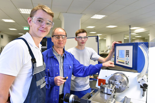 jugendliche Azubis und Ausbilder an einer CNC Drehmaschine - moderne Berufsausbildung im Handwerk // Young apprentices and trainers