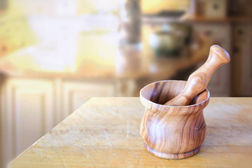 Wooden mortar on a table in a rustic kitchen while preparing a recipe. Empty copy space for...
