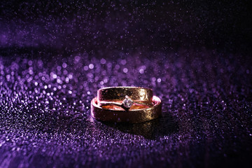 Wedding rings on a purple background with bokeh drops