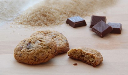 Homemade chocolate chip cookies and ingredients on wooden background. Close up view.