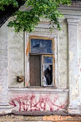 Разбитое окно на серой стене старого дома