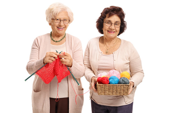 Elderly woman knitting with another elderly woman helping her