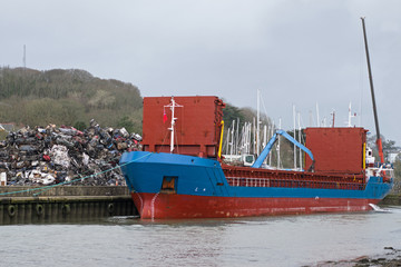 Cargo boat being loaded with crushed metal from scrapped cars at a Cornish port UK