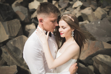 Gorgeous bride, groom kissing and hugging near the cliffs with stunning views
