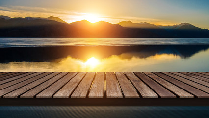 Wooden bridge on the lake with a reflection of sunset on the snow mountain