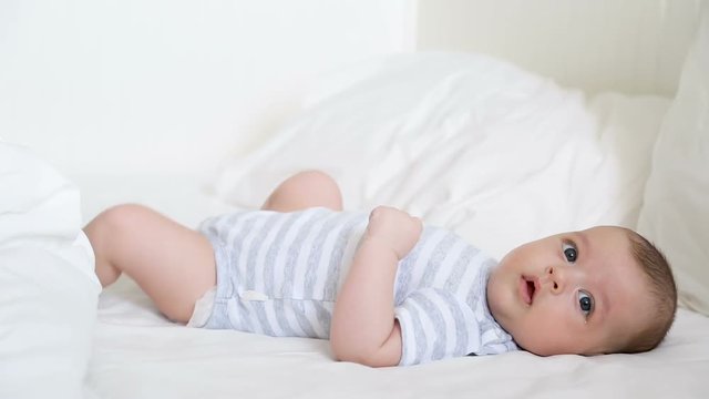 newborn baby lies on the parent white bed with pillows