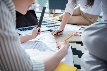 cropped shot of architects working with blueprints and laptop at office
