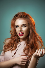 Fototapeta premium Portrait of a beautiful emotional red-haired girl on a blue background