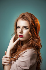 Fototapeta premium Portrait of a beautiful emotional red-haired girl on a blue background