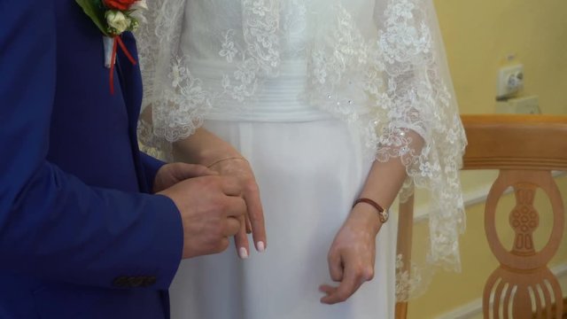Two white people groom and bride exchange wedding rings.