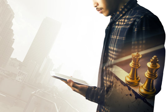 asian business man hold the tablet with two gold chess image double exposure