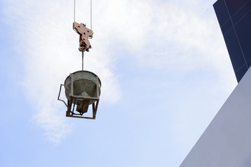 The concrete bucket attach with the hoist with the crane at construction site.Construction equipment.