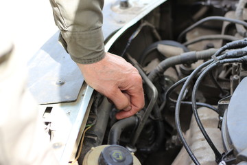 Мужчина занимается профилактикой двигателя автомобиля