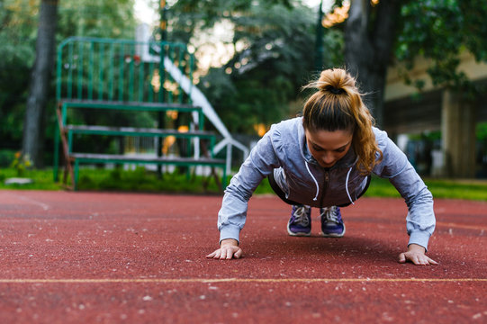 Fitness woman doing push-ups during outdoor cross training workout. - Powered by Adobe