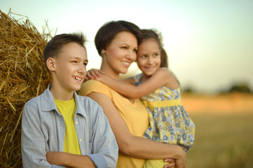 Mother with children near stack of hay 