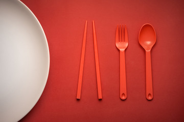 Red Fork/Spoon & chopsticks on red background with white plate.