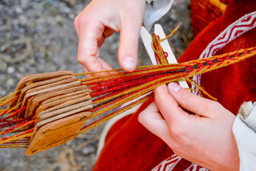 Woman hands weaving a traditional ethnic belt