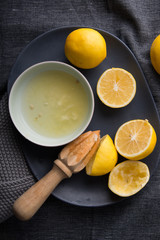 Juicing fresh yellow  lemons on dark moody background top down lay flat