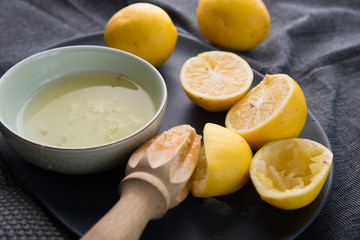 Juicing fresh yellow  lemons on dark moody background