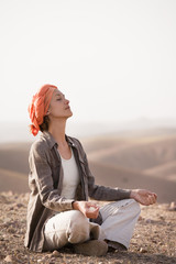 femme assise dans le désert qui fait du yoga