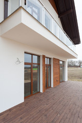 New house with white walls, wooden terrace and .glass balcon