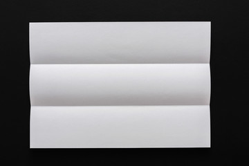 White folded sheet of paper on black background