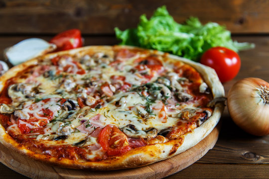 Delicious homemade pizza with mozzarella, mushrooms, tomatoes and ham.