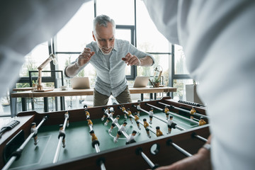 Senior business colleagues playing foosball at office