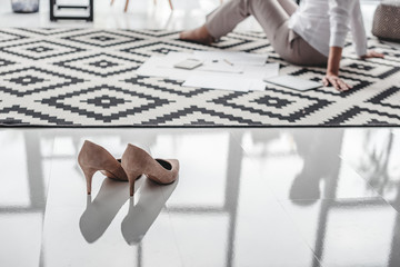 Stilettos and senior businesswoman working with documents on floor in background