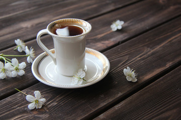 a Cup of coffee and cherry flowers on wooden table