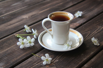 a Cup of coffee and cherry flowers on wooden table