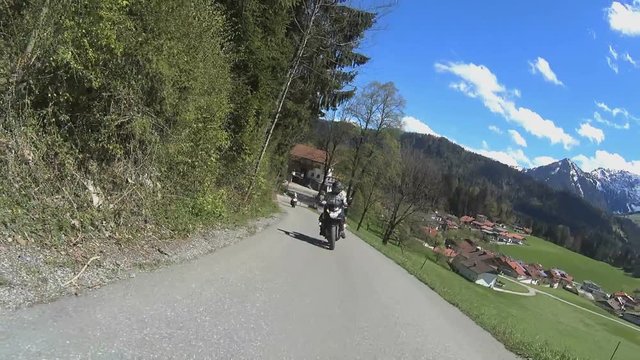 Motorbikes driving on the road in mountains with alps in background