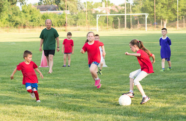 Kids soccer football - boys and girls play football match on soccer field