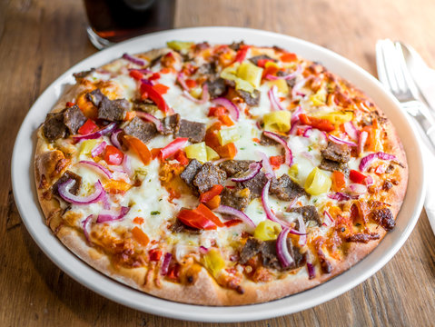 Delicious fresh kebab pizza dinner served on plate on wooden table