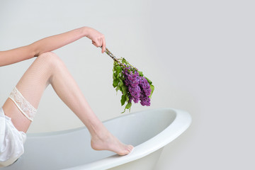 hand with lilac and leg on bathtub