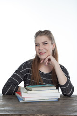 Student women sitting on wood table with her hands and shoulder on the books. Smiling Girl with books, on wooden table and white background. Close-up on white background.