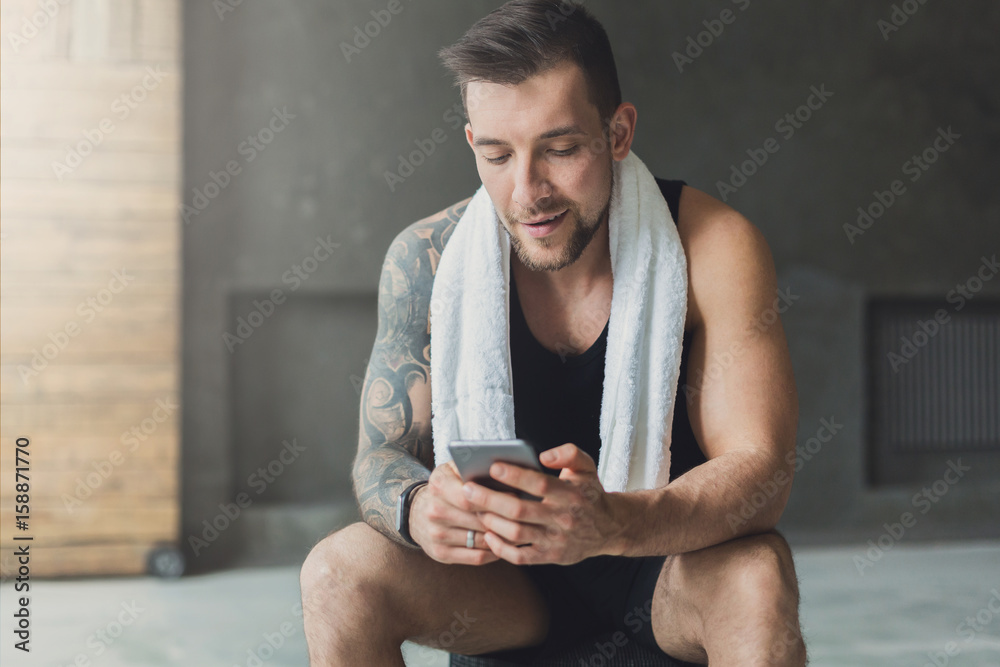 Wall mural handsome man use mobile phone in gym